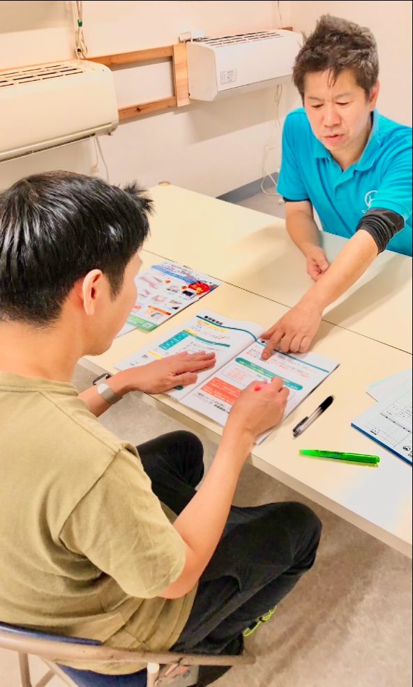 講師が受講生にエアコンの養生方法を指導している様子