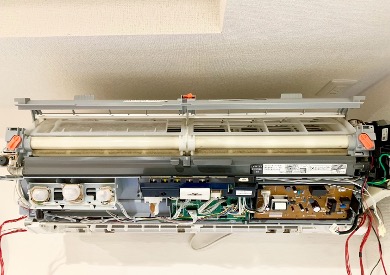 講師が受講生にエアコン内部の部品分解を指導している様子